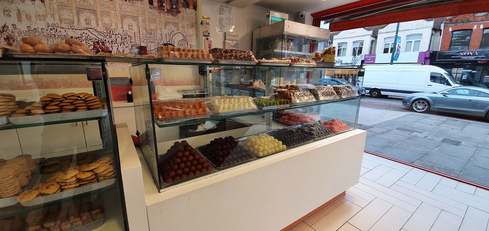 Inside Original Gourmet of Lahore — sweet cases and cookie shelves with the Ilford Lane shopfront window